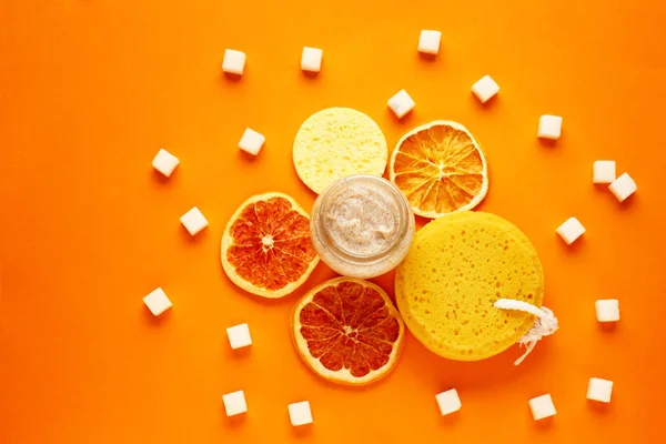 Jar of sugar scrub with citrus slices on color background