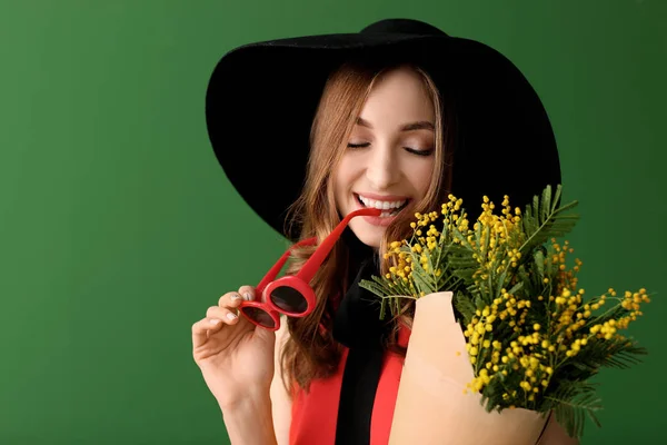 Beautiful young woman with bouquet of mimosa flowers on color background — Stock Photo, Image