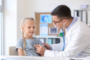 Pediyatrist küçük kızı klinikte muayene ediyor.