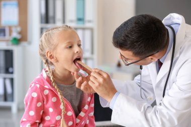 Pediyatrist küçük kızı klinikte muayene ediyor.