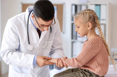 Pediyatrist küçük kızı klinikte muayene ediyor.