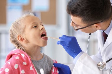 Pediyatrist küçük kızı klinikte muayene ediyor.