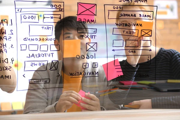 Diseñadores de TI discutiendo proyecto, ver a través de tablero transparente — Foto de Stock