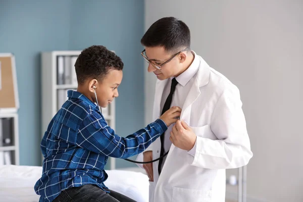 Menino afro-americano brincando com estetoscópio no consultório do pediatra — Fotografia de Stock