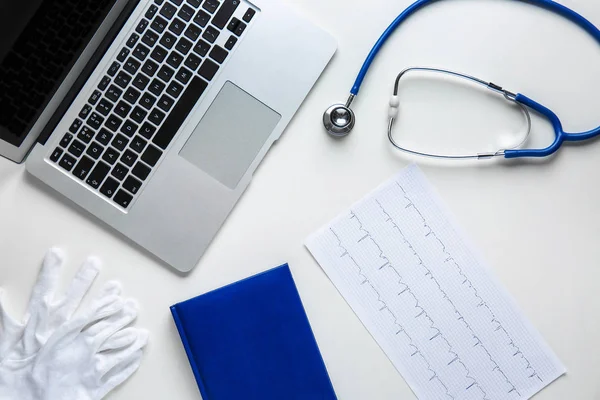 Ordenador portátil, estetoscopio, cardiograma y guantes en la mesa —  Fotos de Stock