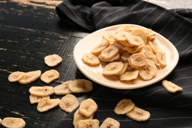 Plaka karanlık masada lezzetli kurutulmuş muz ile