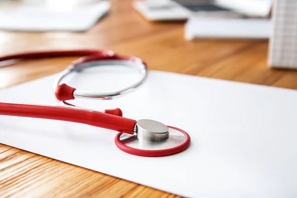 Stethoscope with sheet of paper on doctor's table, closeup — Stock Photo, Image