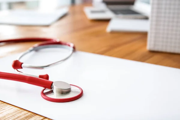 Estetoscopio con hoja de papel en la mesa del médico, primer plano —  Fotos de Stock