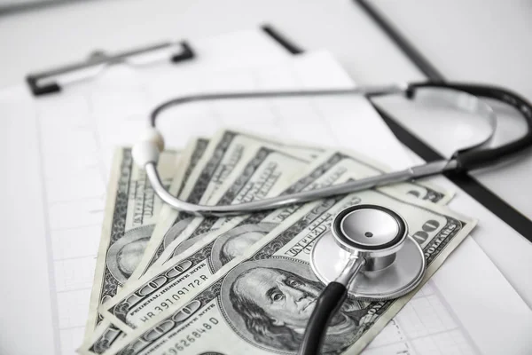 Stethoscoop met geld en cardiogram op doctor's tafel, close-up — Stockfoto