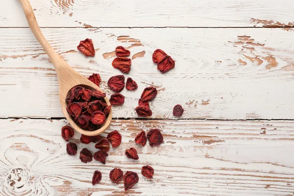 Spoon with tasty dried strawberry on white wooden background — Stock Photo, Image