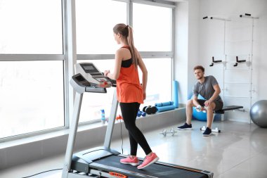 Spor salonundaki koşu bandında antrenman yapan genç bir kadın.