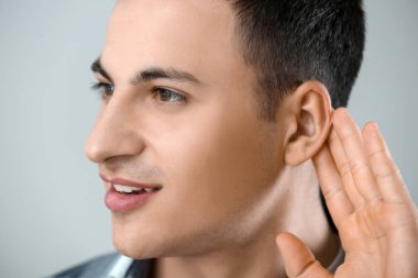 Gri arka plan, closeup işitme sorunu olan genç adam
