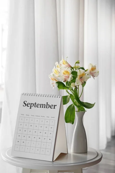 Flip calendar and vase with bouquet of flowers on table — Stock Photo, Image