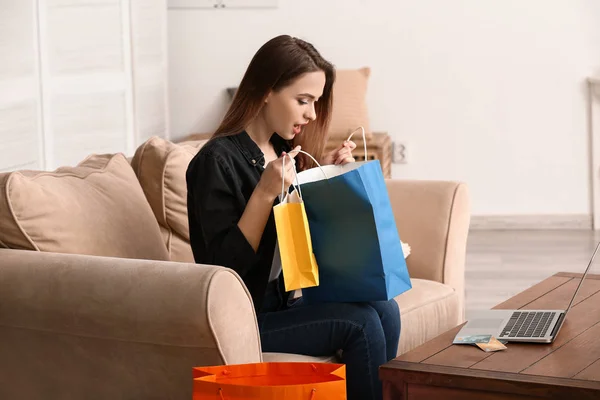 Surprised woman looking into shopping bag at home