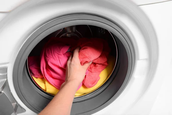 Woman putting dirty laundry in washing machine, closeup