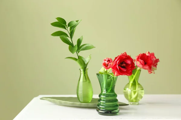 Jarrones con hermosas flores en la mesa contra el fondo de color — Foto de Stock