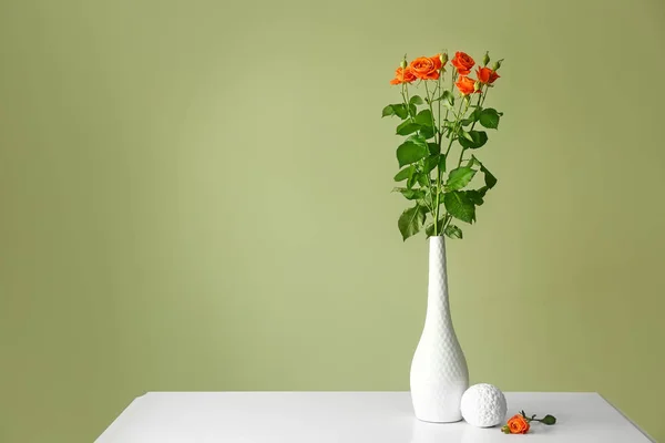 Vase with beautiful flowers on table against color background — Stock Photo, Image