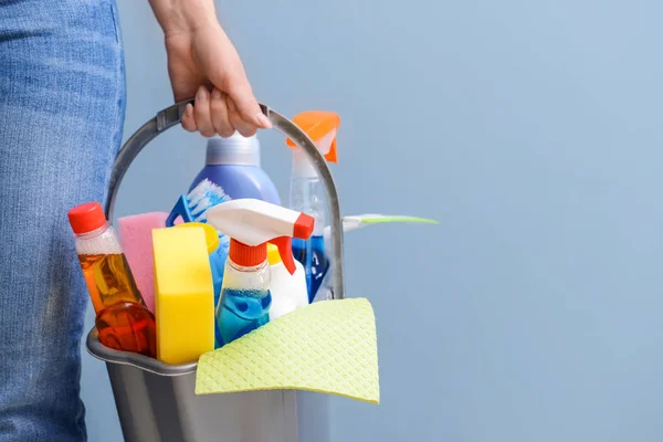 Woman with set of cleaning supplies on color background — Stock Photo, Image