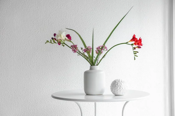 Vase with beautiful flowers on table against white background — Stock Photo, Image