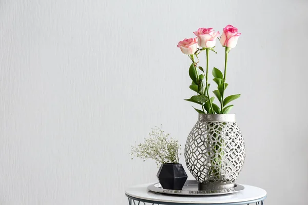 Vases with beautiful flowers on table against white background — Stock Photo, Image