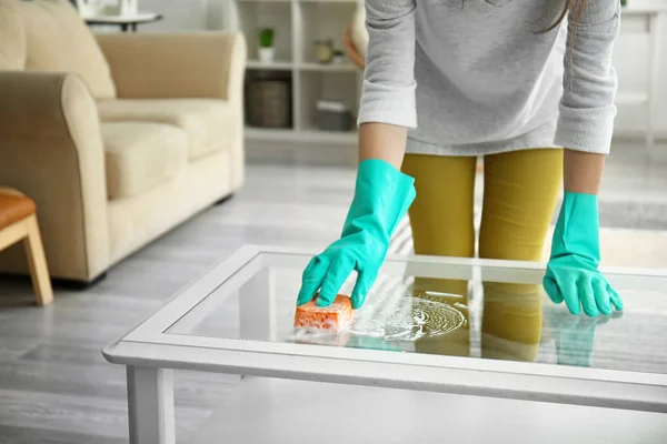 Молодая женщина моет стеклянный стол дома — стоковое фото