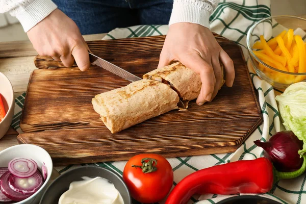 Mujer cortando sabroso doner kebab en la mesa —  Fotos de Stock