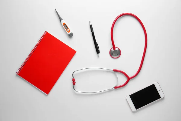 Stethoscope, notebook, mobile phone and thermometer on white background — Stock Photo, Image