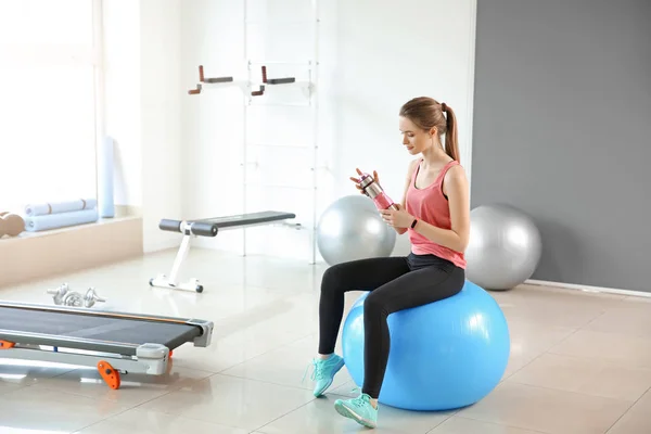 Sporty young woman drinking water in gym — Stock Photo, Image