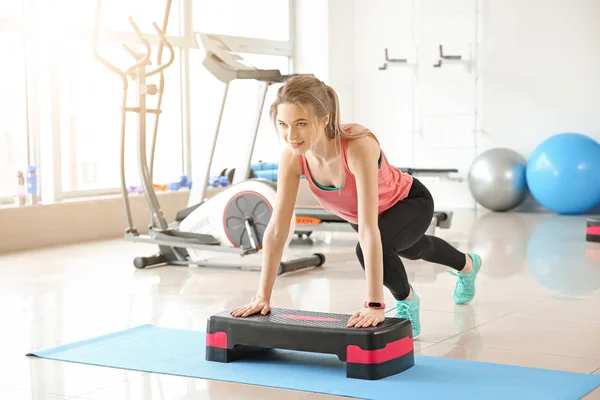 Deportiva joven entrenando con stepper en el gimnasio —  Fotos de Stock