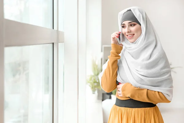 美丽的穆斯林妇女在窗口附近通过电话交谈 — 图库照片