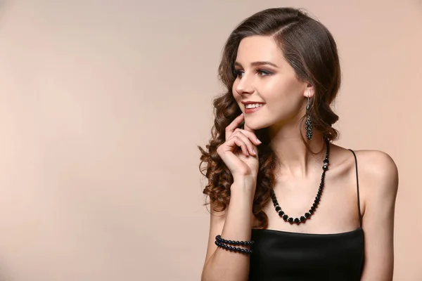 Giovane donna con bellissimi gioielli su sfondo a colori — Foto Stock