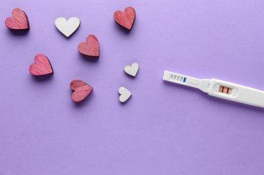 Renk arka planda gebelik testi ve kalpler