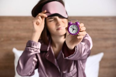Uyku maskesi ve çalar saat yatakta olan memnun kadın