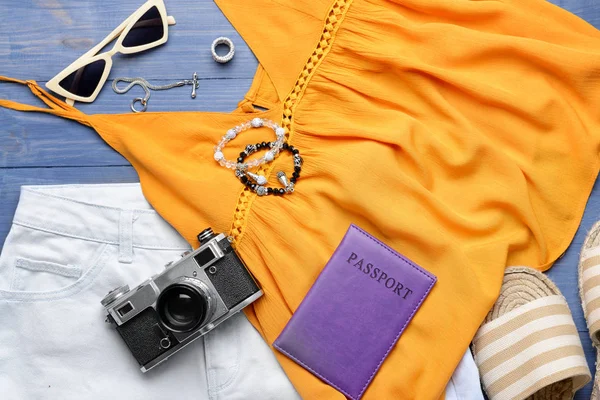 Roupas femininas com acessórios, passaporte e câmera fotográfica em fundo de madeira — Fotografia de Stock