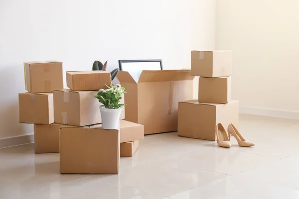 Moving boxes with belongings in empty room — Stock Photo, Image