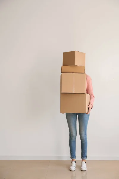 Vrouw met bewegende dozen in de buurt van lichte muur in de kamer — Stockfoto