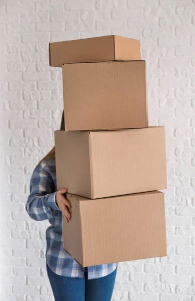 Женщина с движущимися коробками возле кирпичной стены — стоковое фото