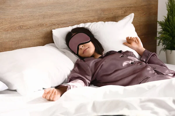 Young woman with sleep mask in bed — Stock Photo, Image