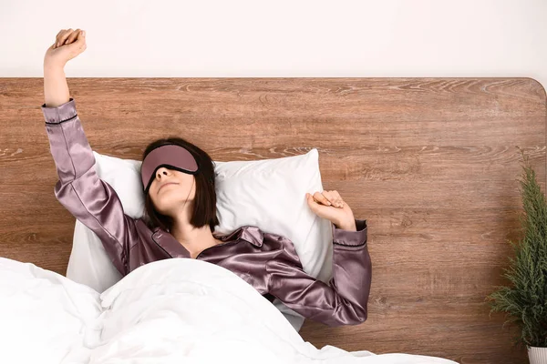 Mujer joven con máscara de sueño en la cama —  Fotos de Stock