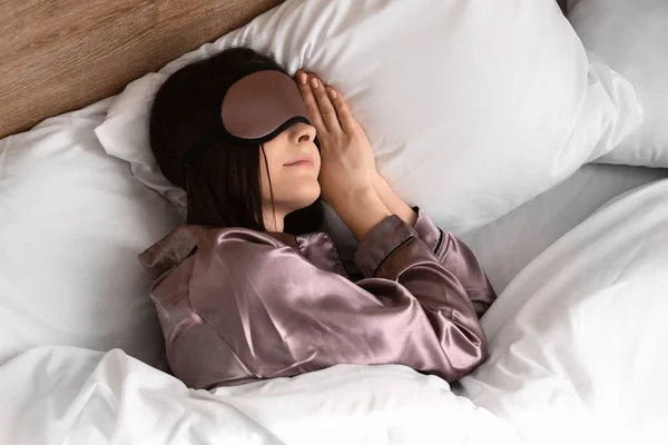 Jonge vrouw met slaap masker in bed — Stockfoto