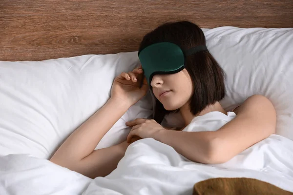 Young woman with sleep mask in bed — Stock Photo, Image