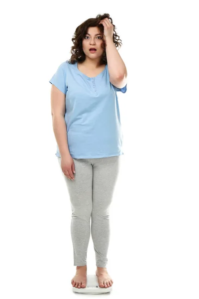 Schockierte übergewichtige Frau steht auf Waage vor weißem Hintergrund — Stockfoto
