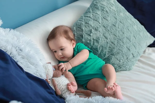 Adorable baby boy with toy sitting on soft sofa at home — Stock Photo, Image