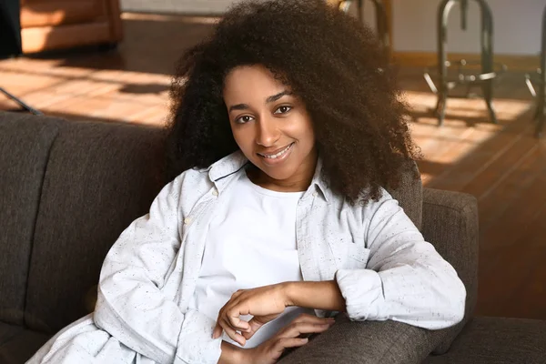 Portrait of beautiful African-American woman resting on sofa at home — Stock Photo, Image