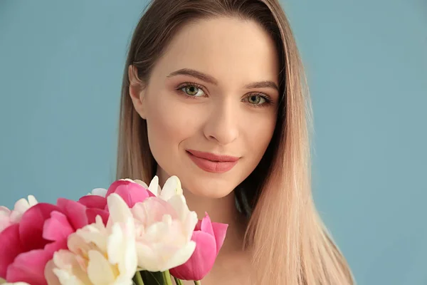 Jovem com buquê de belas tulipas no fundo de cor — Fotografia de Stock