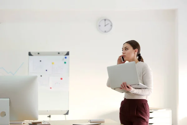 Бізнес-леді з ноутбуком розмовляють по телефону в офісі — стокове фото