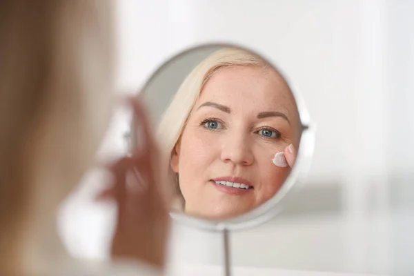 Reife Frau, die zu Hause Gesichtscreme aufträgt — Stockfoto