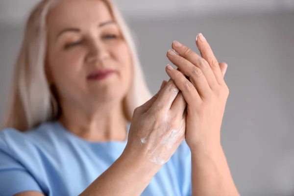 Mature woman applying hand cream at home — Stock Photo, Image