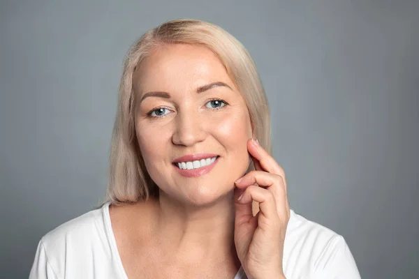 Reife Frau mit gesunder Haut auf grauem Hintergrund — Stockfoto