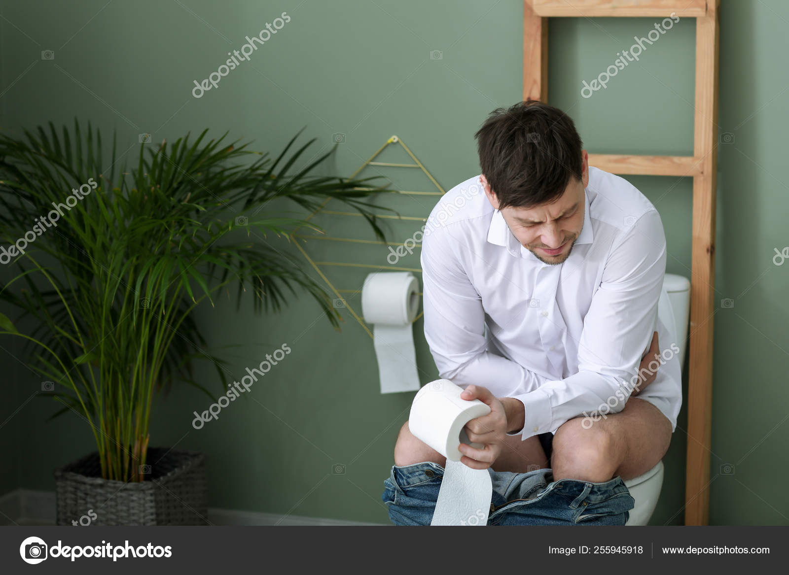 Man suffering from diarrhea while sitting on toilet bowl at home Stock